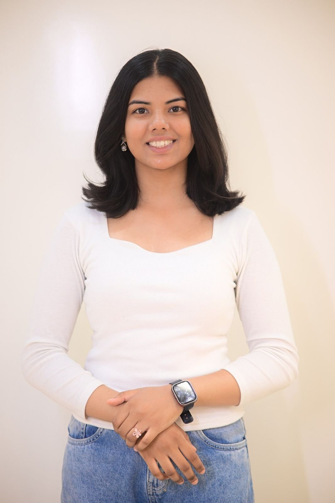 Woman with a shoulder-length layered cut, smiling in a white top
