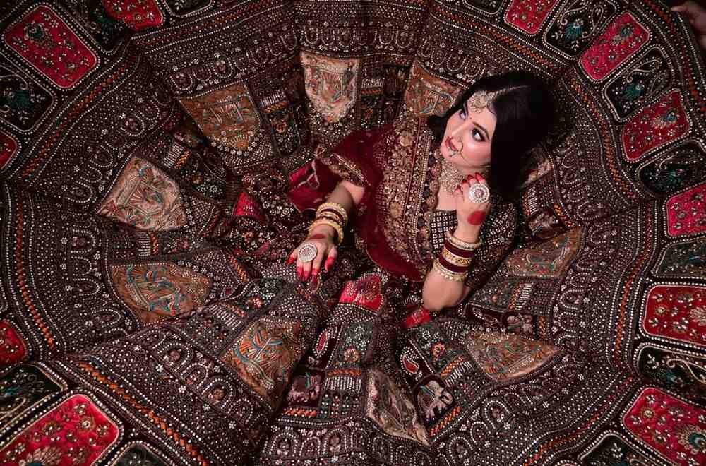Overhead view of a bride seated on a spread embroidered lehenga