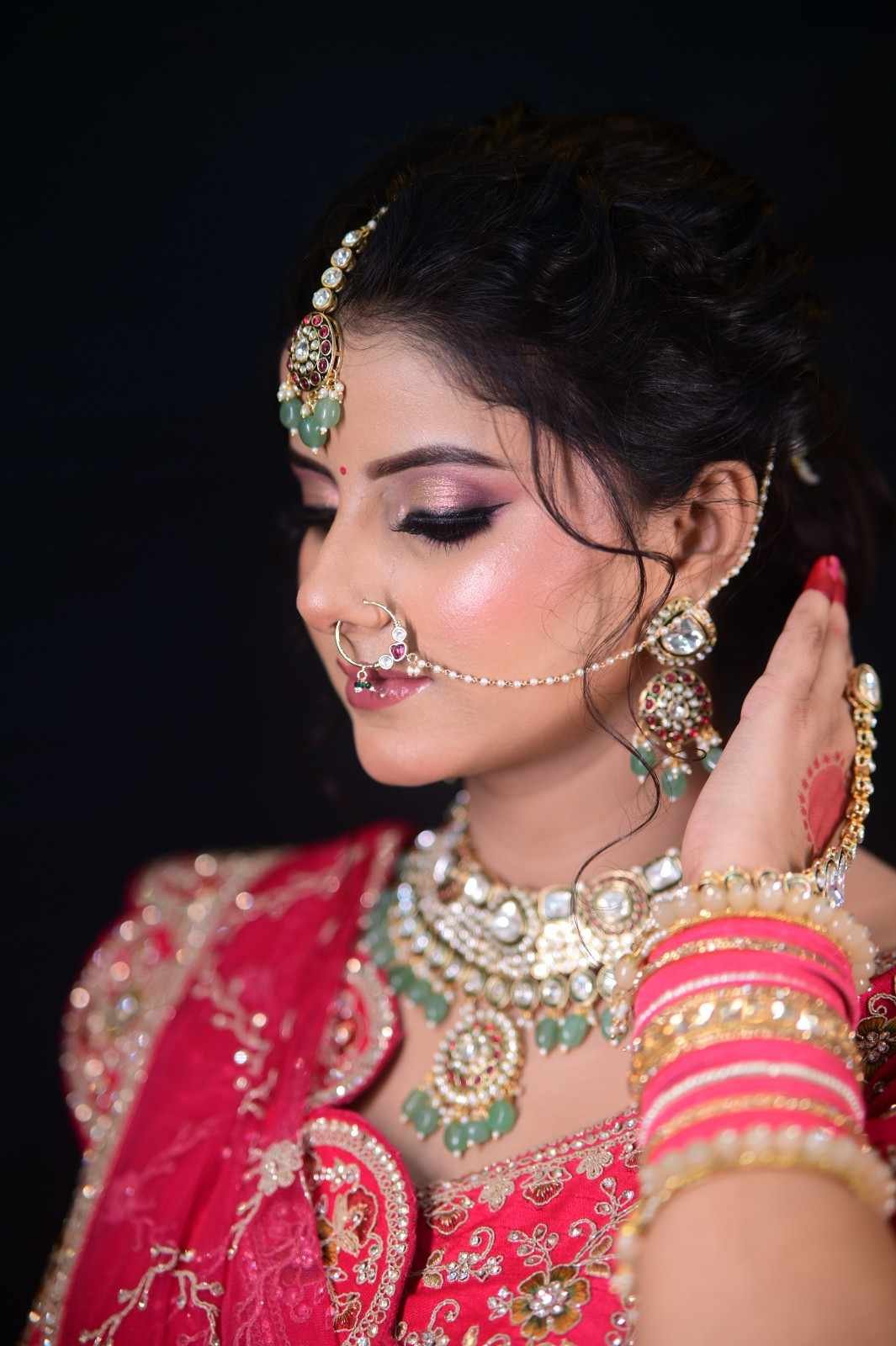 Bridal portrait in profile wearing a red lehenga with green kundan jewellery and a maang tikka