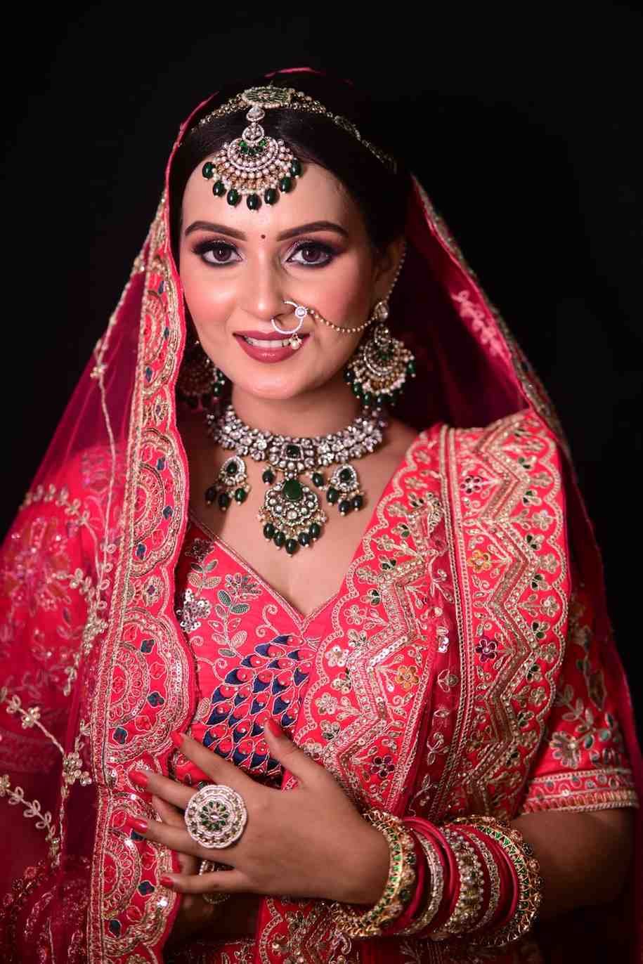 Bride in a red lehenga with a ring and bangles, hand raised to her cheek