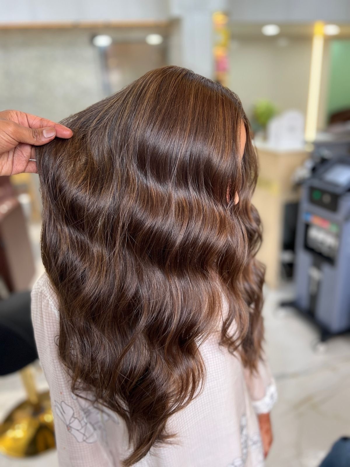 Long brown hair styled in loose waves, held up at the ends by a stylist