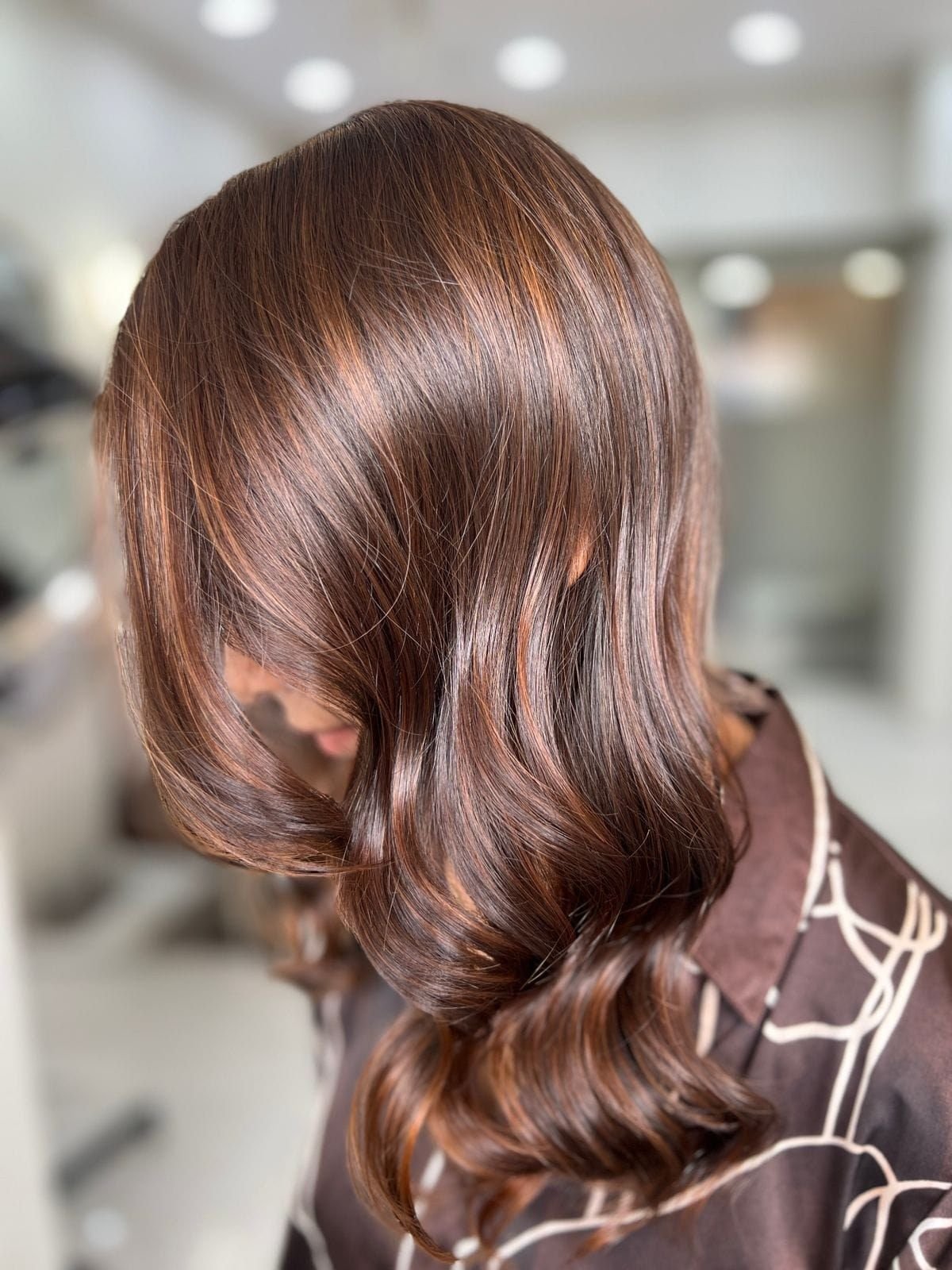 Glossy brown hair styled in soft waves with warm highlights