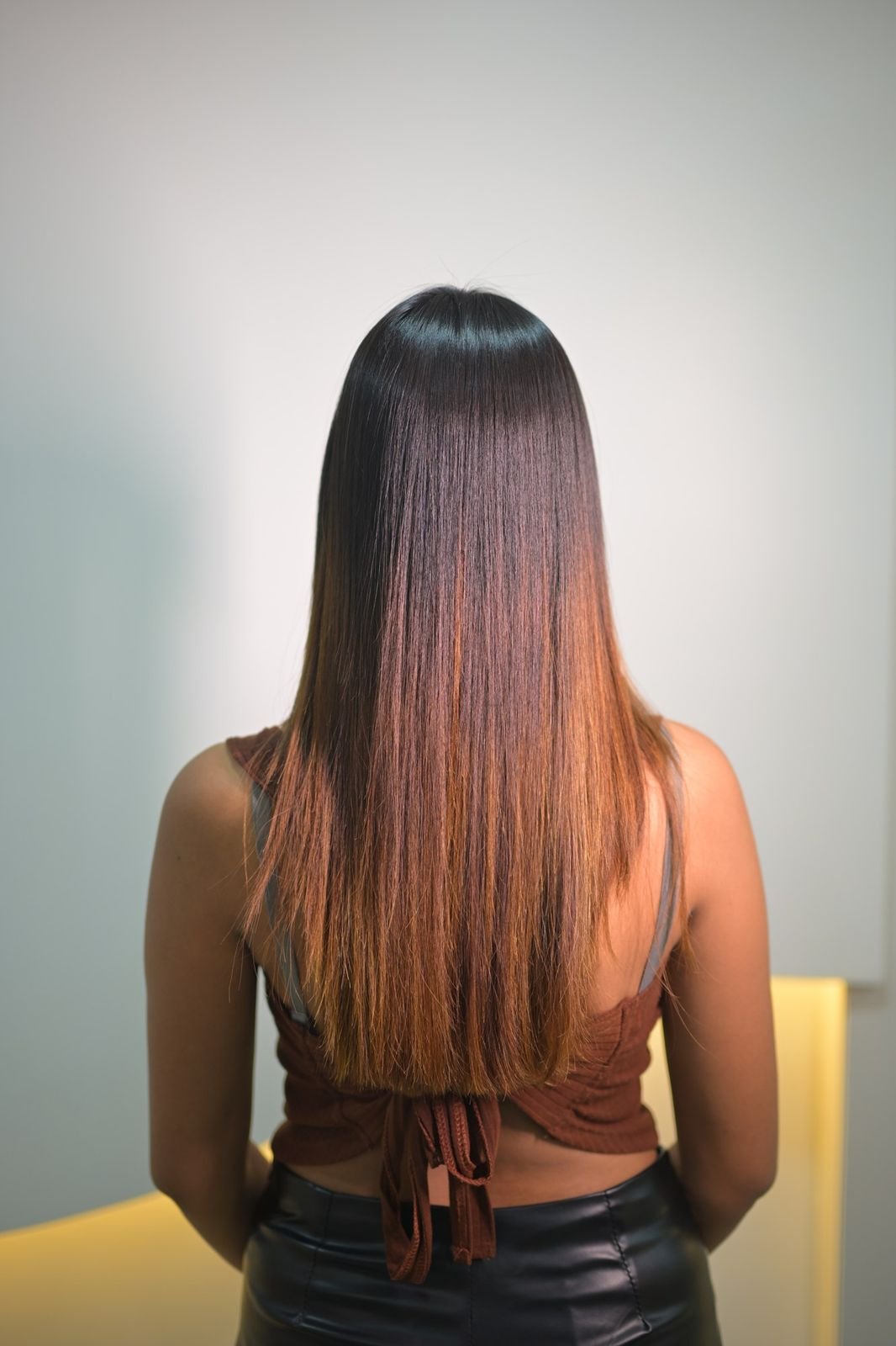 Back view of straight hair that darkens at the roots and lightens to copper at the ends