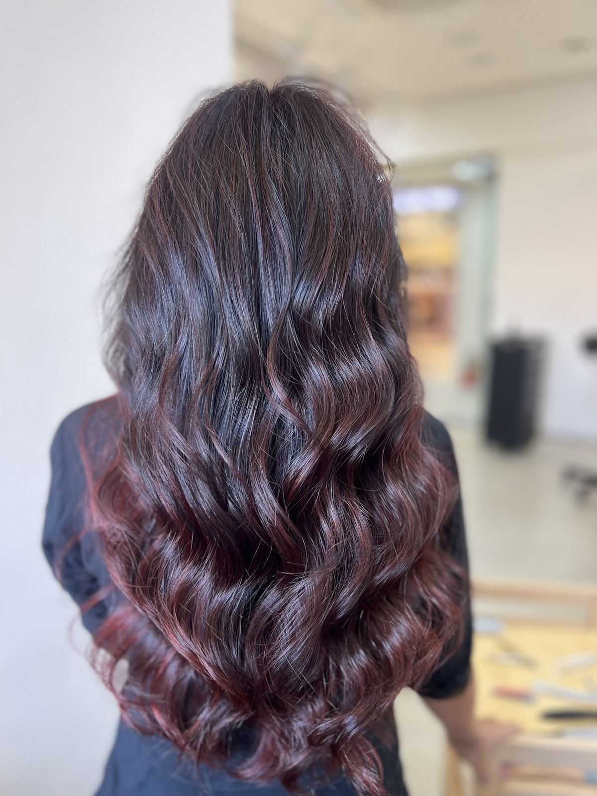 Back view of long wavy hair with dark roots and wine-red ends