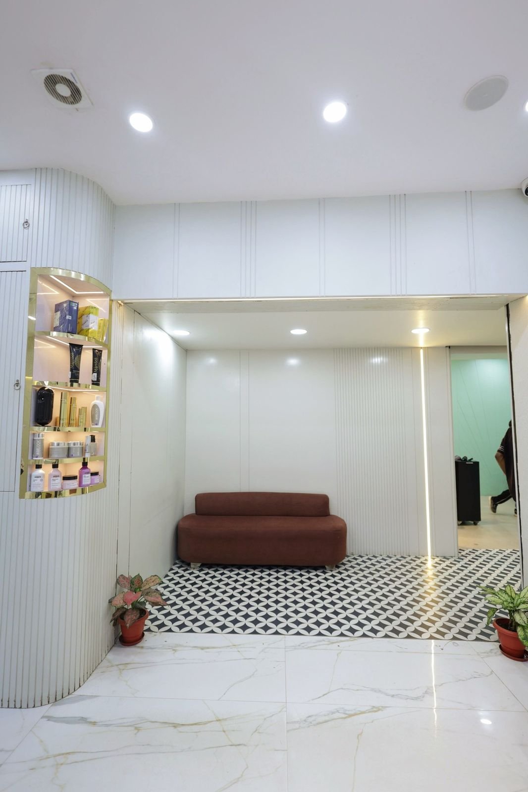 Waiting area with a brown sofa, display shelves and a black and white patterned floor