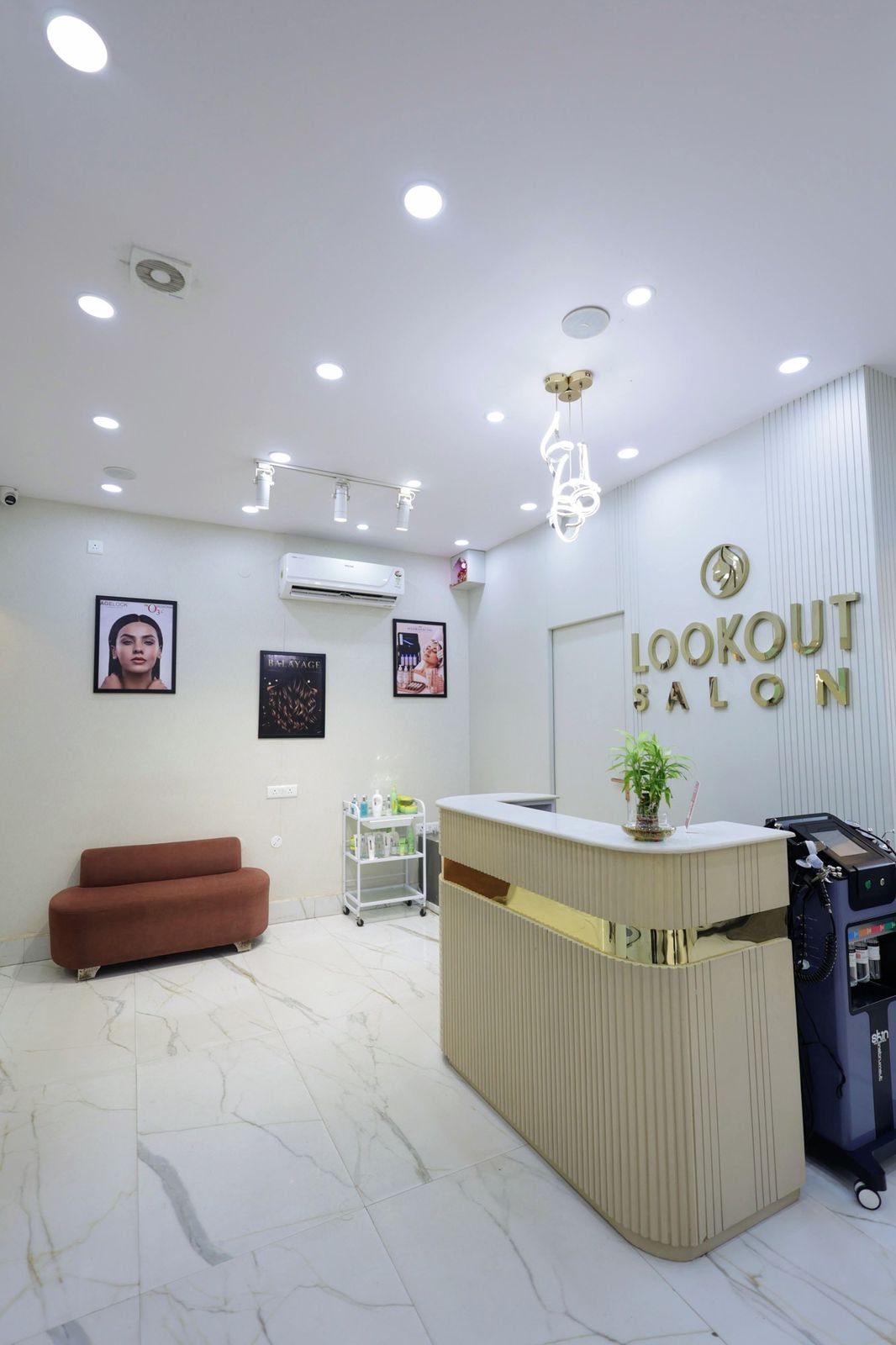 Reception desk with the LookOut Salon sign, a sofa and white marble flooring