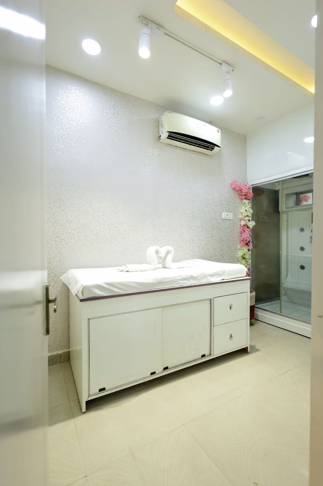 Treatment room with a white treatment bed, a wall air conditioner and a shower cubicle