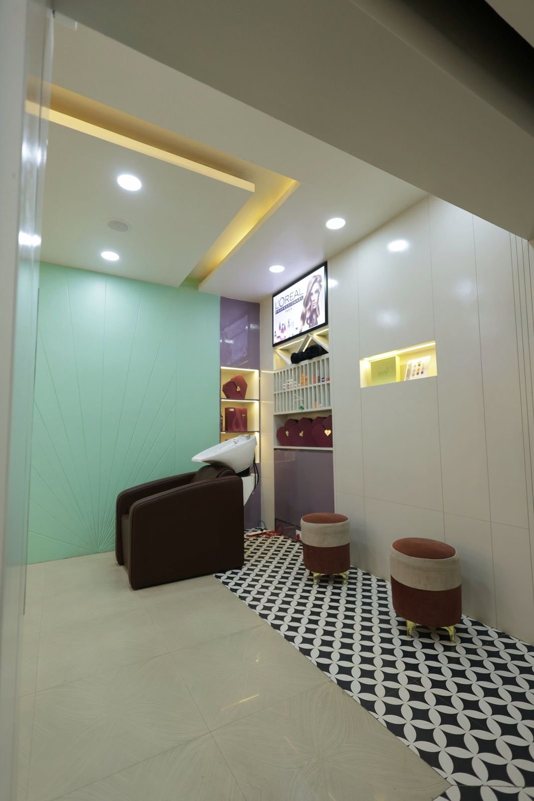 Hair wash area with a brown wash chair beside a green wall and a wall-mounted screen