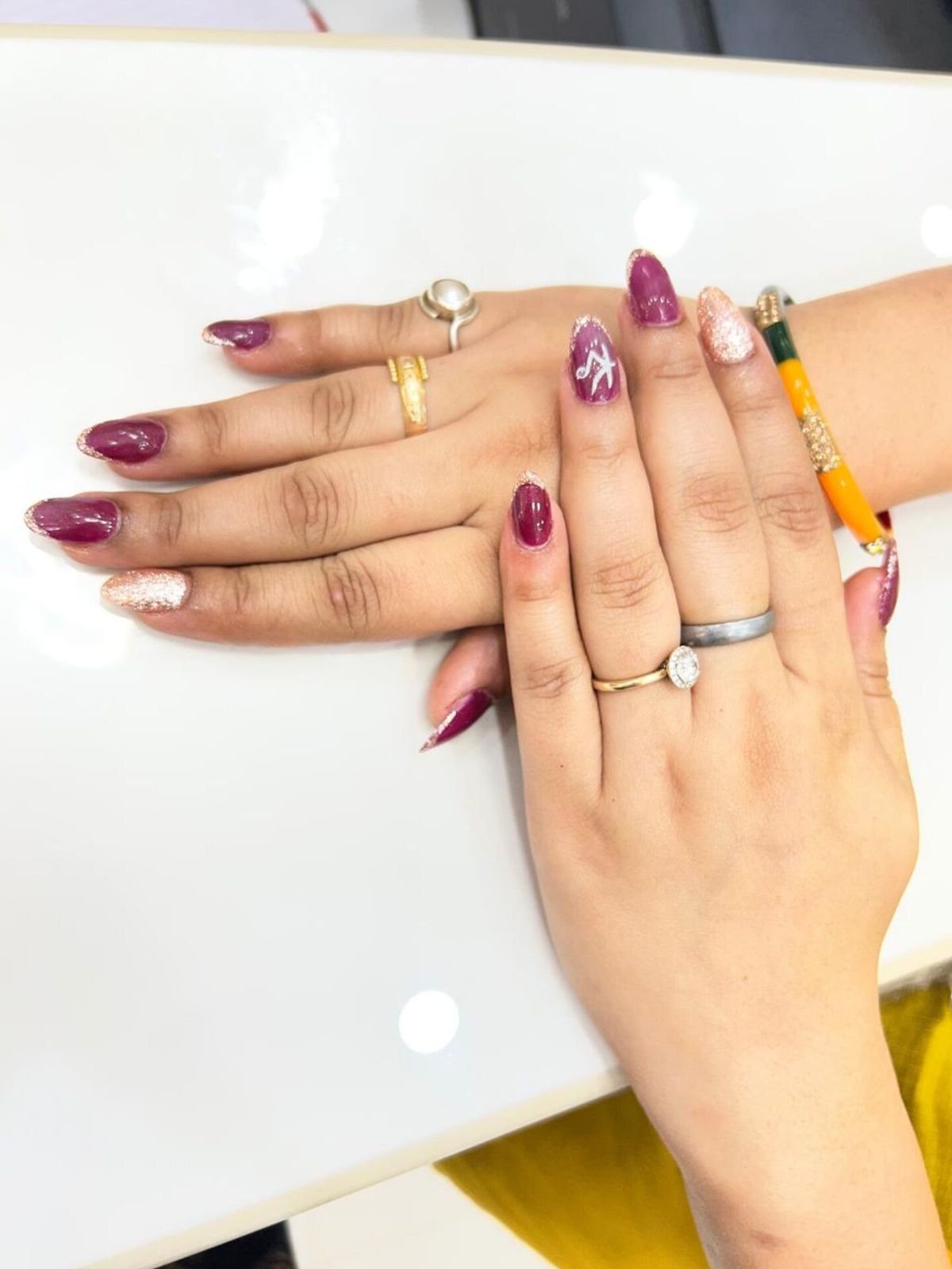 Two hands with berry and white nail colours