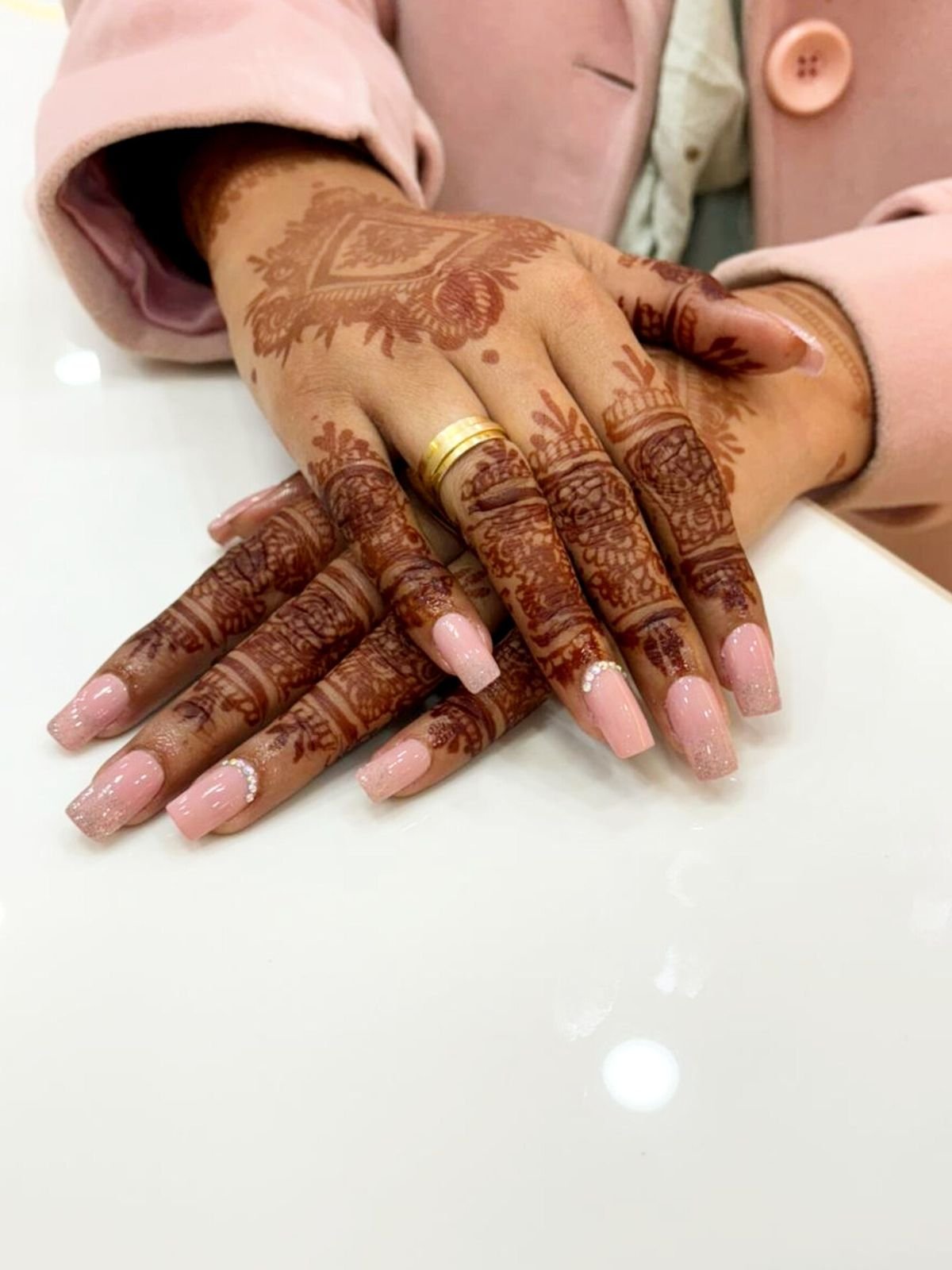 Hands with a detailed mehndi design and light pink nails