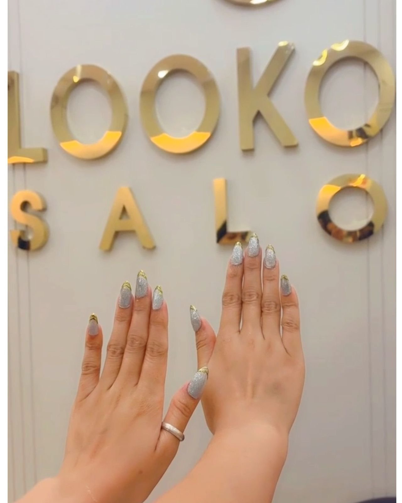 Hands with silver nails held up in front of the LookOut Salon lettering
