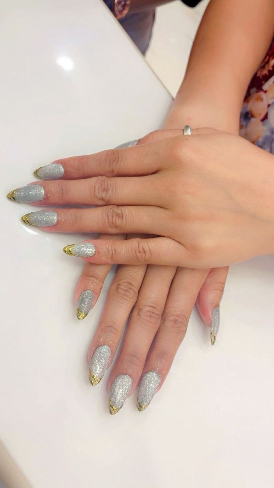 Hands with long silver nails with gold tips